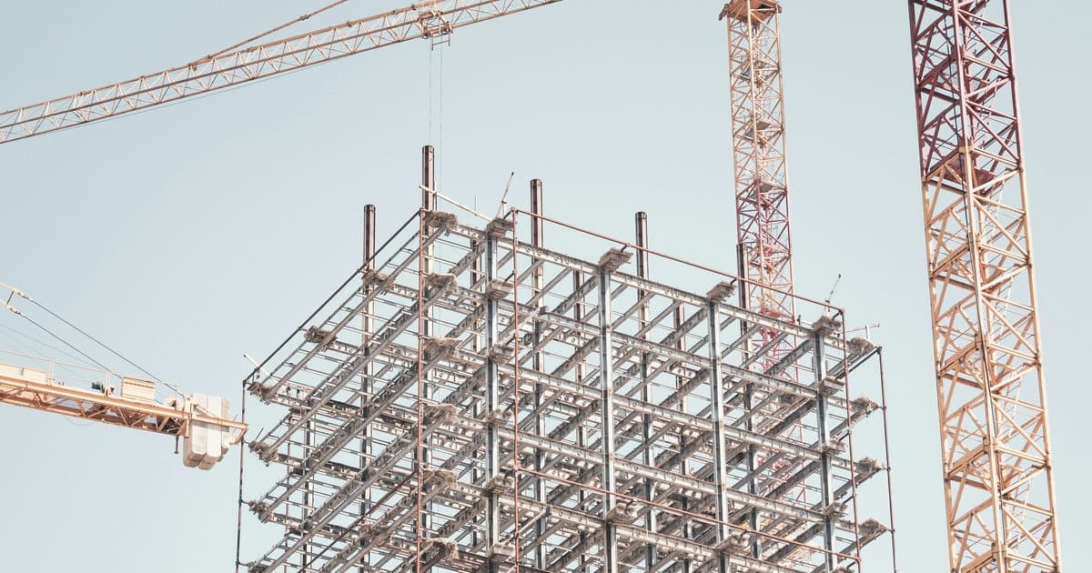 Steel building frame under construction beside a tower crane.