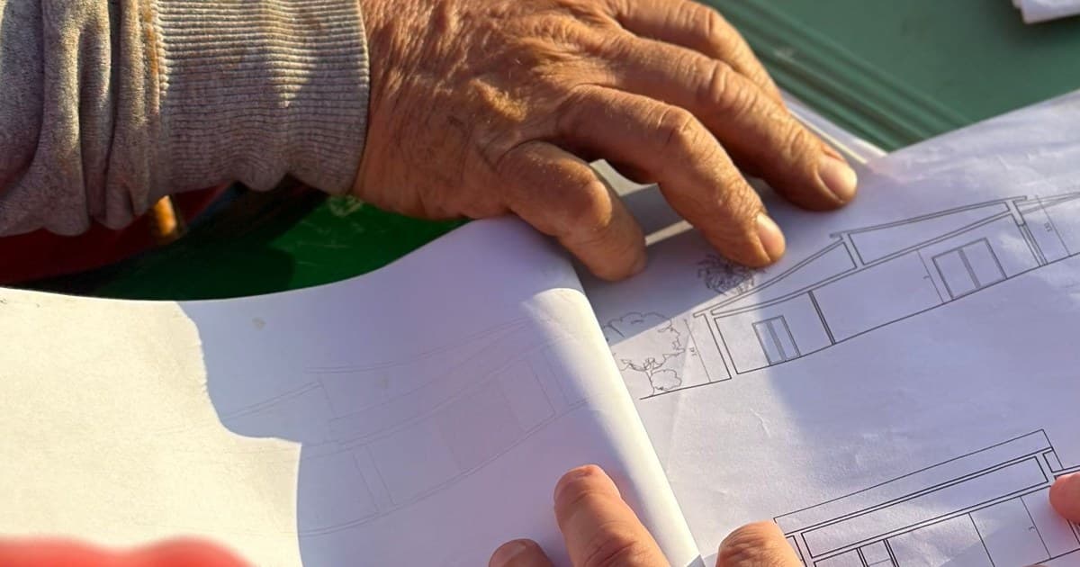 A team examining construction drawings together at an outdoor site.